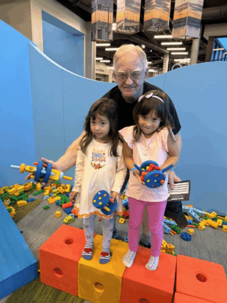 Grandpa with two grand daughters holding up foam block creations.